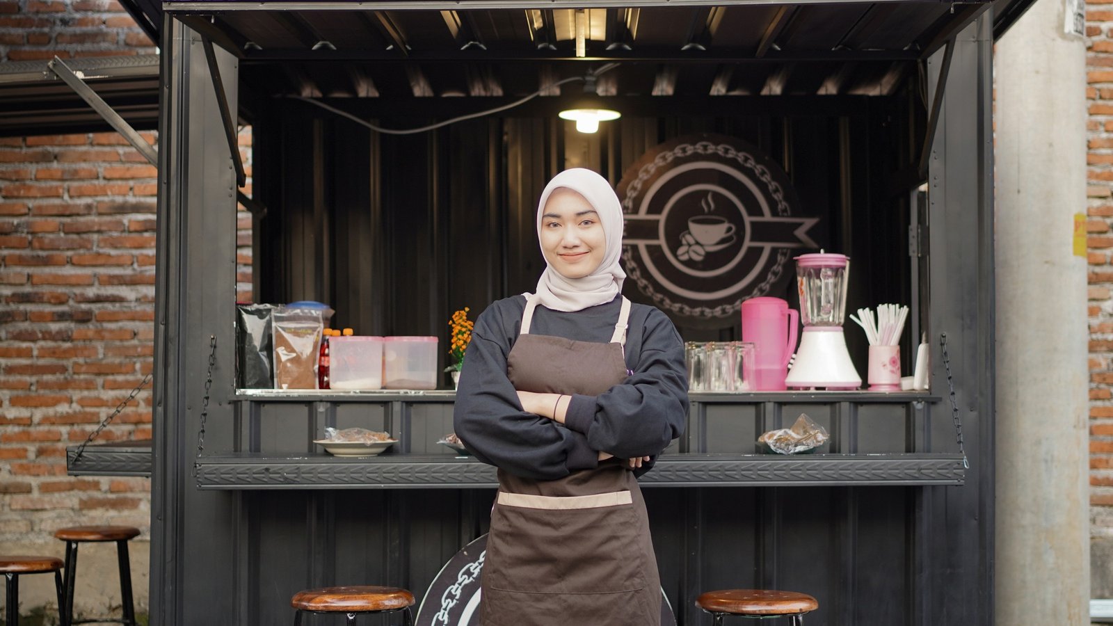 Beautiful Asian waitress with arms ready to serve at the cafe booth container